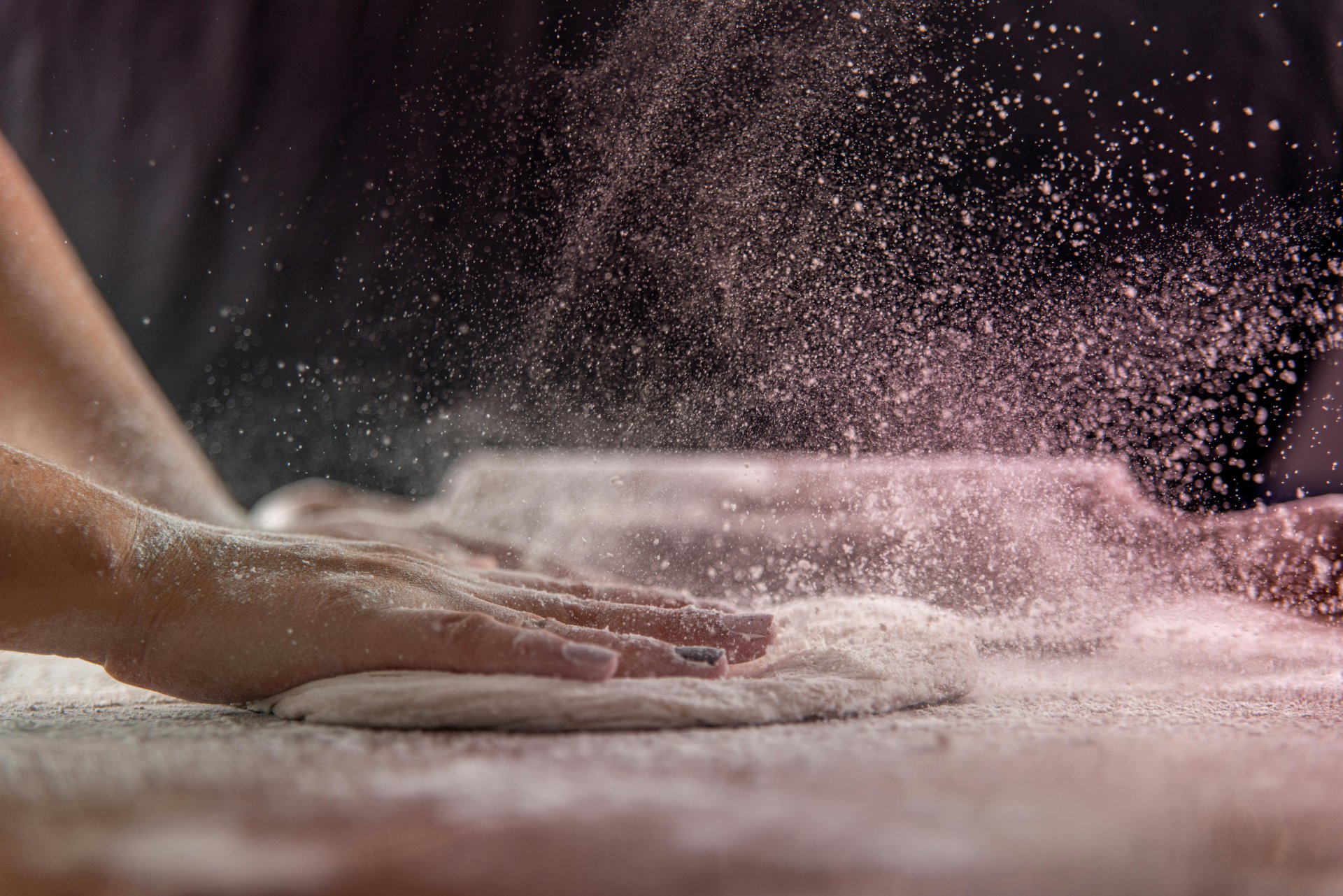 Hands kneading bread dough on a floured surface